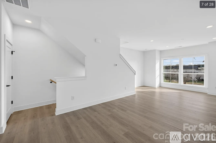 A spacious room with wooden flooring and a staircase leading to another level.