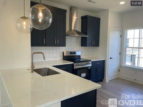 A kitchen with a white counter top and black cabinets is for sale.