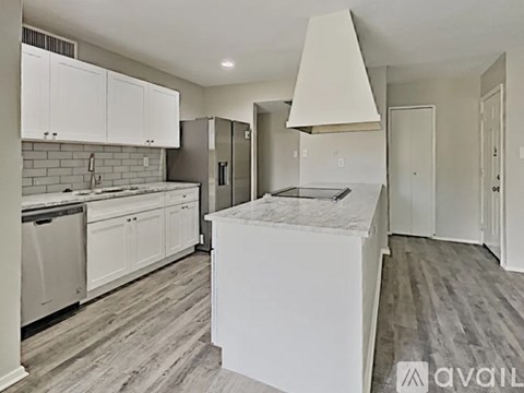 A modern kitchen with white cabinets and a marble island.
