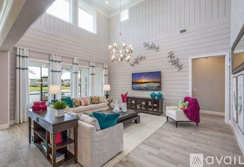 A well-lit, spacious living room with a large painting on the wall and a comfortable seating area.