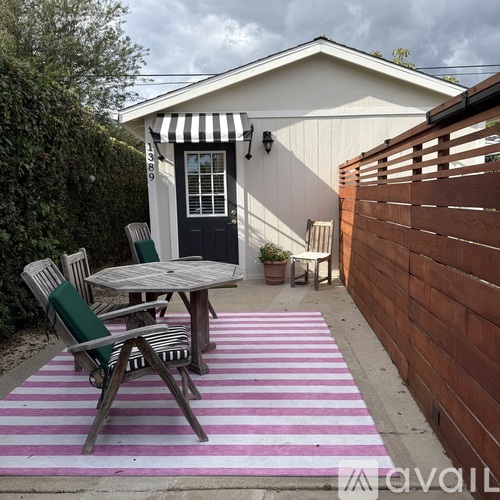 A patio with a striped rug and a table with chairs.