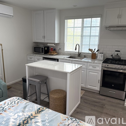 A kitchen with white cabinets and a white island with a countertop.