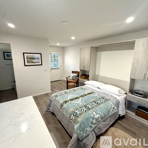 A bedroom with a large bed and a framed picture on the wall.