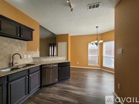 A kitchen with dark brown cabinets and a marble countertop.