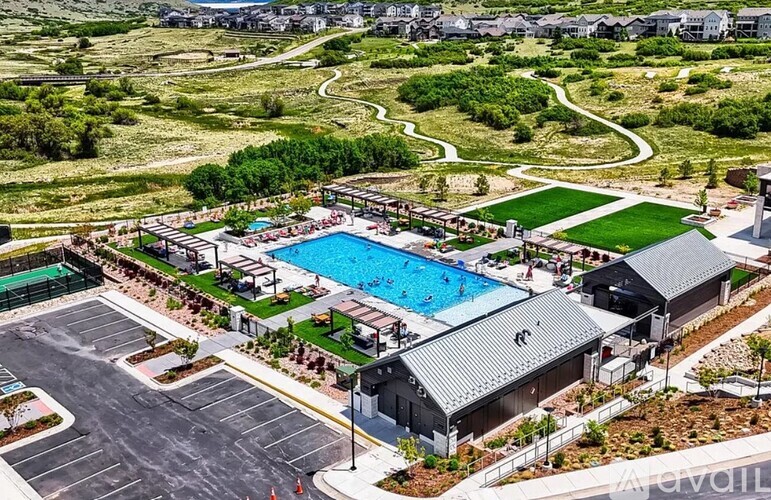 A large outdoor swimming pool surrounded by a grassy area and a parking lot.