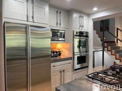 A modern kitchen with a stainless steel refrigerator and a stove top oven.