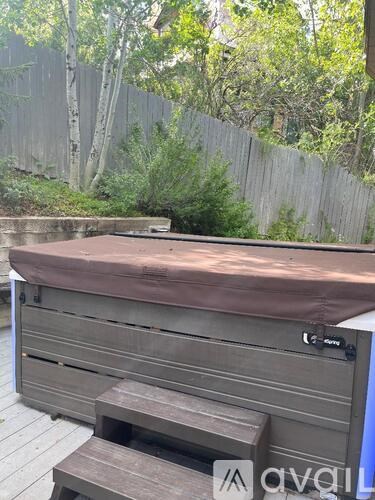 A hot tub on a wooden deck surrounded by a fence.