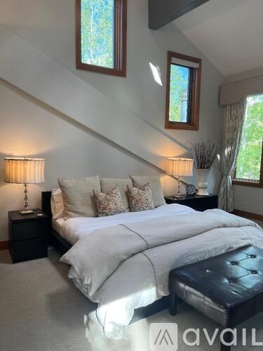 A bedroom with a large bed and two lamps.