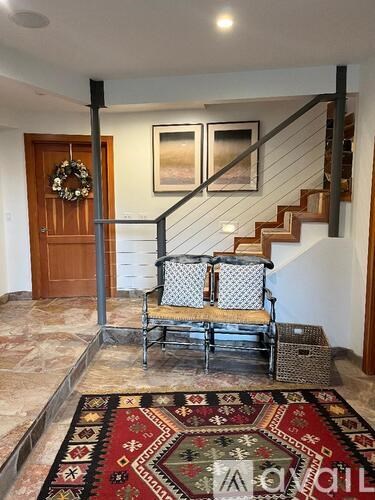A living room with a rug and a chair.