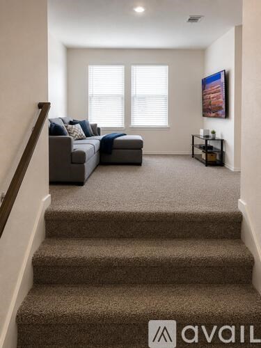 A living room with a couch, a staircase, and a painting on the wall.
