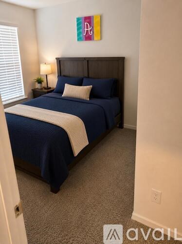 A bedroom with a bed, nightstand, and lamp.