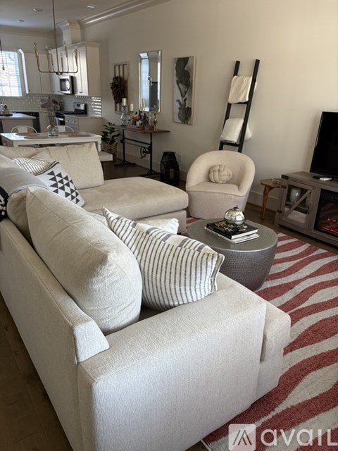 A living room with a white couch and a striped rug.