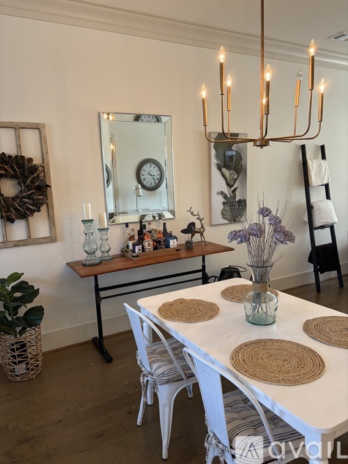 A dining room with a white table and chairs, a mirror, and a wreath on the wall.