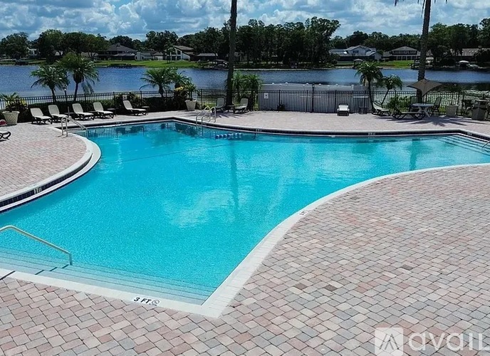 A swimming pool surrounded by a brick patio and a metal fence.