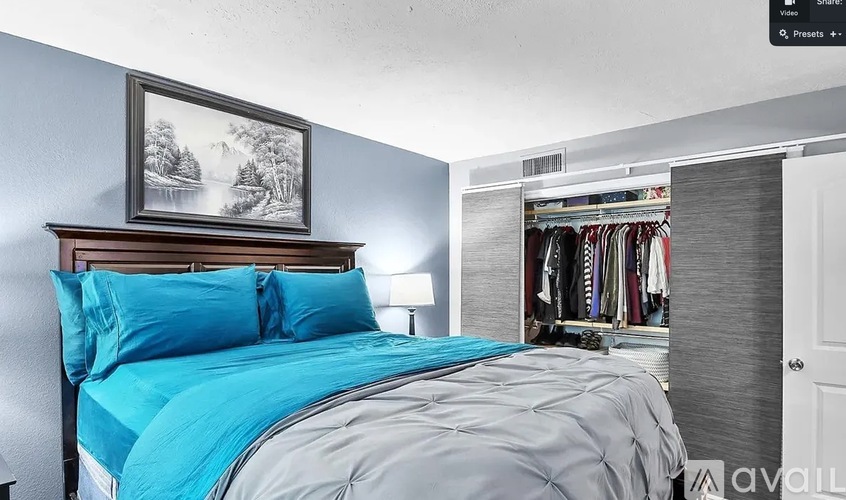 A bedroom with a bed, a lamp, and a painting on the wall.