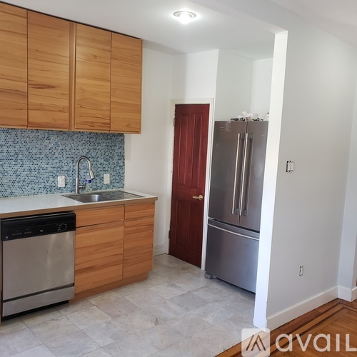 A kitchen with wooden cabinets and a stainless steel refrigerator.