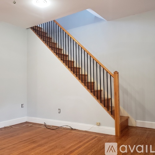 A wooden staircase with a black railing in a white room.