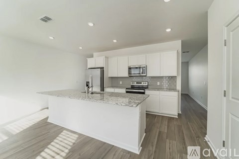 A modern kitchen with white cabinets and a marble island.