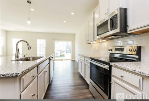 A modern kitchen with white cabinets and black appliances.
