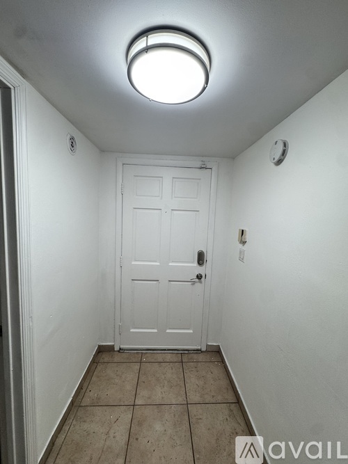 A white door is in a hallway with a clock on the wall.