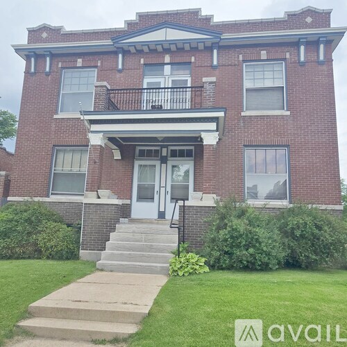 A red brick house with a white door and a balcony.