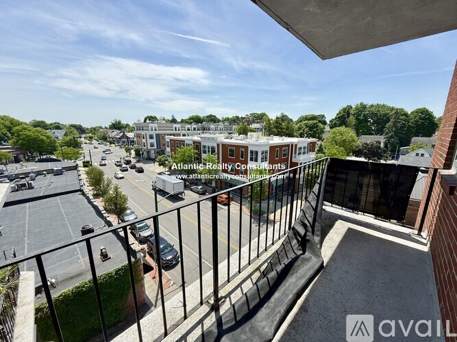 A balcony overlooks a street with cars and buildings.