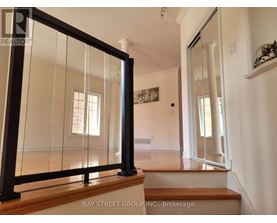 A glass door with a black frame is in the foreground of a white room.
