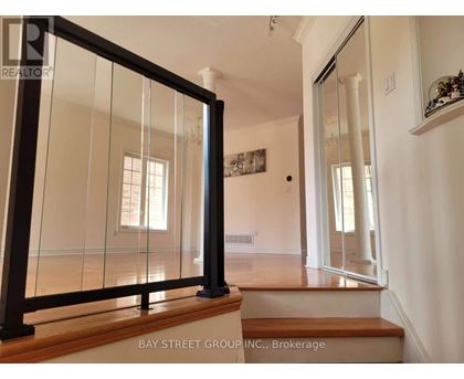 A glass door with a black frame is in the foreground of a white room.