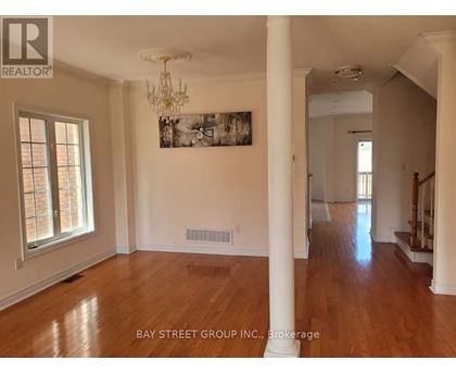 A spacious room with wooden floors and white walls, with a chandelier hanging from the ceiling.