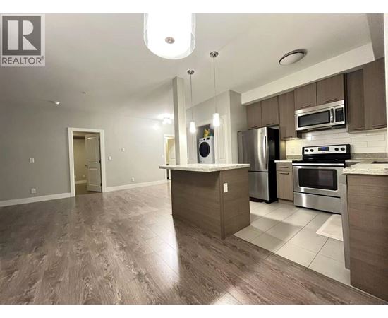 A modern kitchen with a wooden floor and stainless steel appliances.