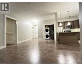 A spacious room with a kitchen area in the background.