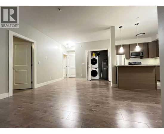 A spacious room with a kitchen area in the background.