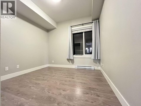 A room with a window and a wooden floor.