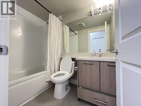 A white toilet in a bathroom with a white tub and a white sink.