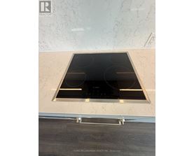 A modern kitchen with a marble backsplash and a stove top oven.