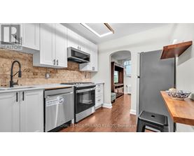 A kitchen with white cabinets and a brick wall.