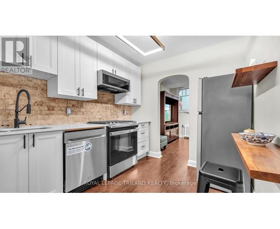 A kitchen with white cabinets and a brick wall.