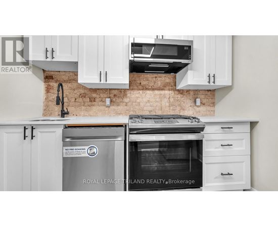 A kitchen with white cabinets and a brick wall.