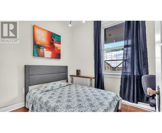 A bedroom with a bed, a chair, and a painting on the wall.