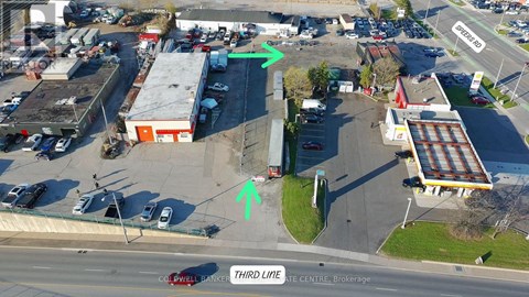 An aerial view of a parking lot with a green arrow pointing to a building and a red arrow pointing to a tree.