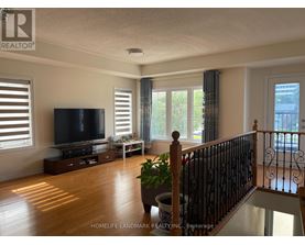 A living room with a television, a plant, and a staircase.