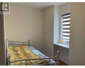 A bedroom with a bed and a window with blinds.