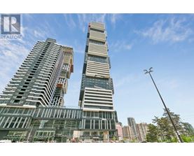 A tall building with a glass facade stands in front of a skyline.