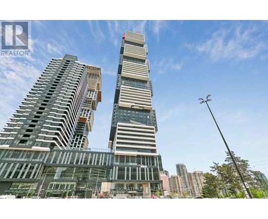 A tall building with a glass facade stands in front of a skyline.