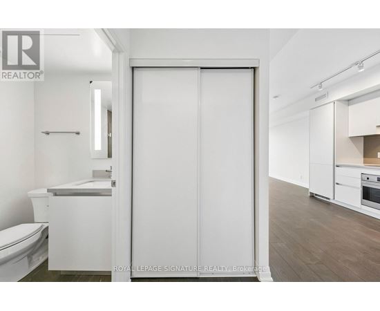 A white bathroom with a toilet, sink, and a large white door.