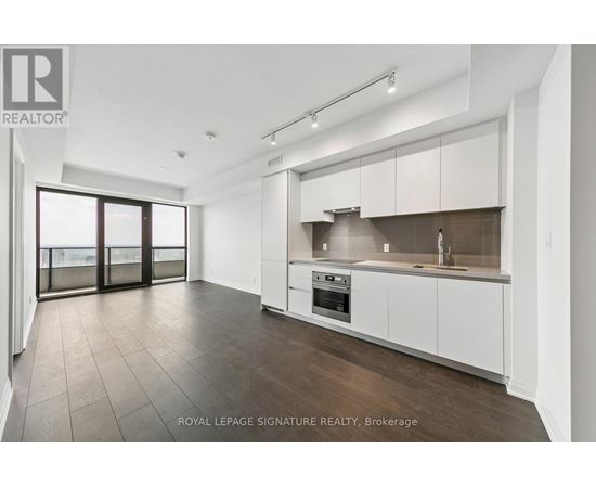 A spacious kitchen with white cabinets and a dark countertop.
