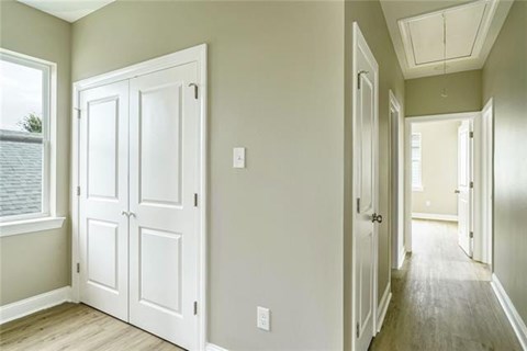 A hallway with a white door and a window.