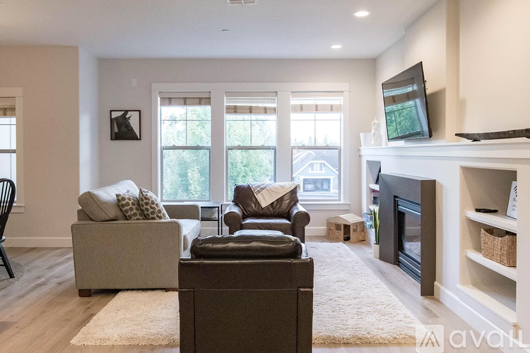 A living room with a brown leather couch and a white fireplace.