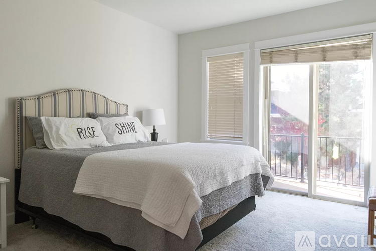 A bedroom with a bed, pillows, and a lamp.
