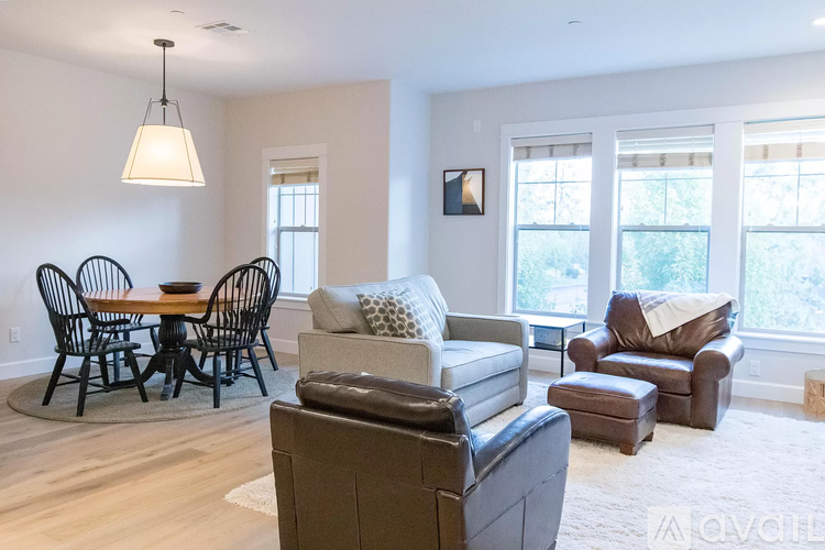 A living room with a brown leather couch and a round wooden table with four chairs.